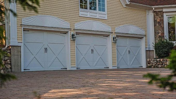 There are three garage doors on the side of a house.