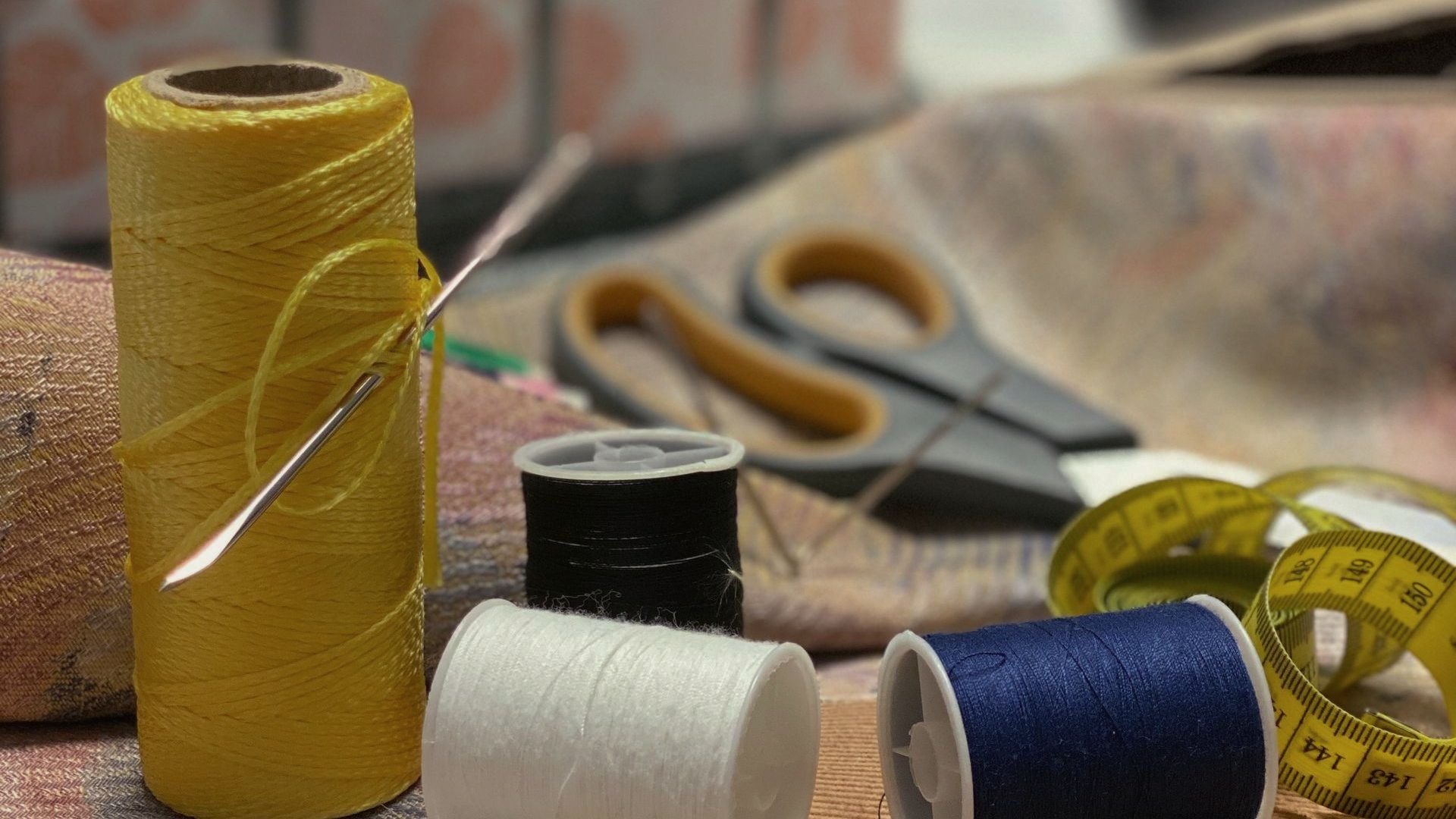 Ein Nähtisch mit Garnrollen, Schere und Maßband.