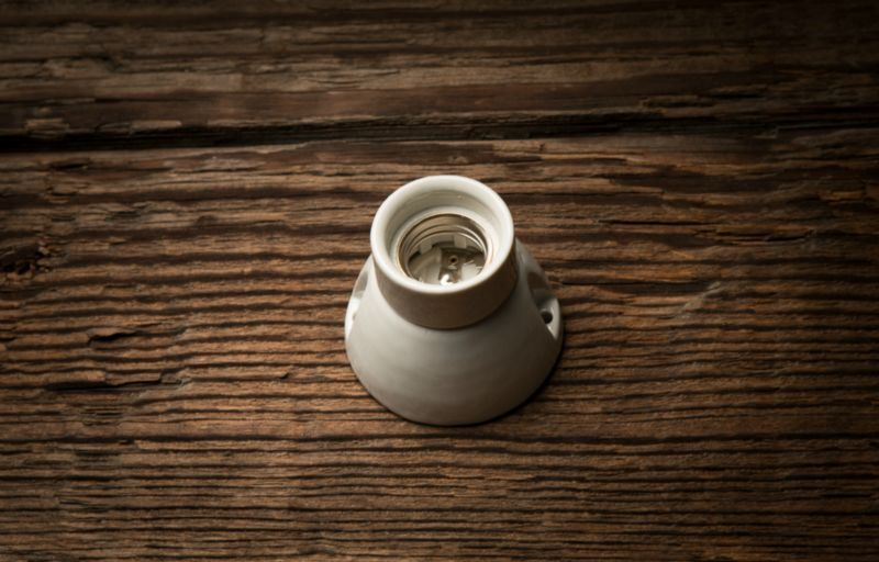 Auf einem Holztisch steht eine weiße Glühbirnenfassung.