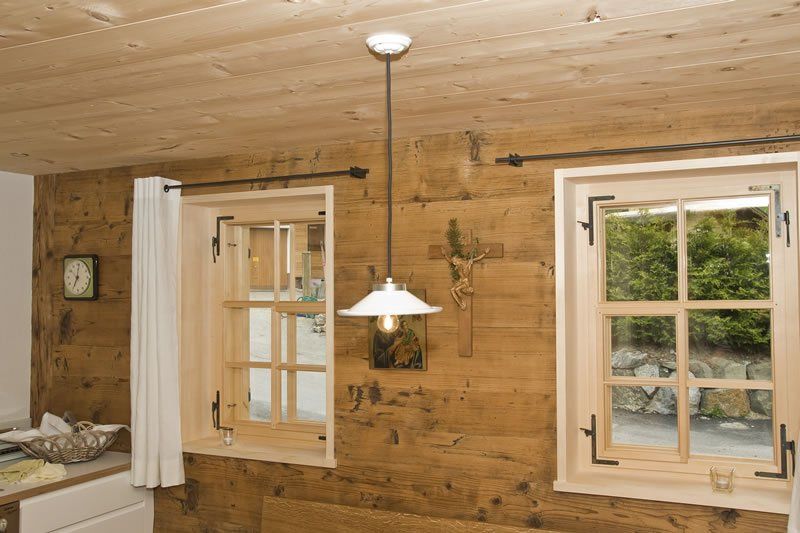 Eine Holzwand mit zwei Fenstern und einer Lampe, die von der Decke hängt.