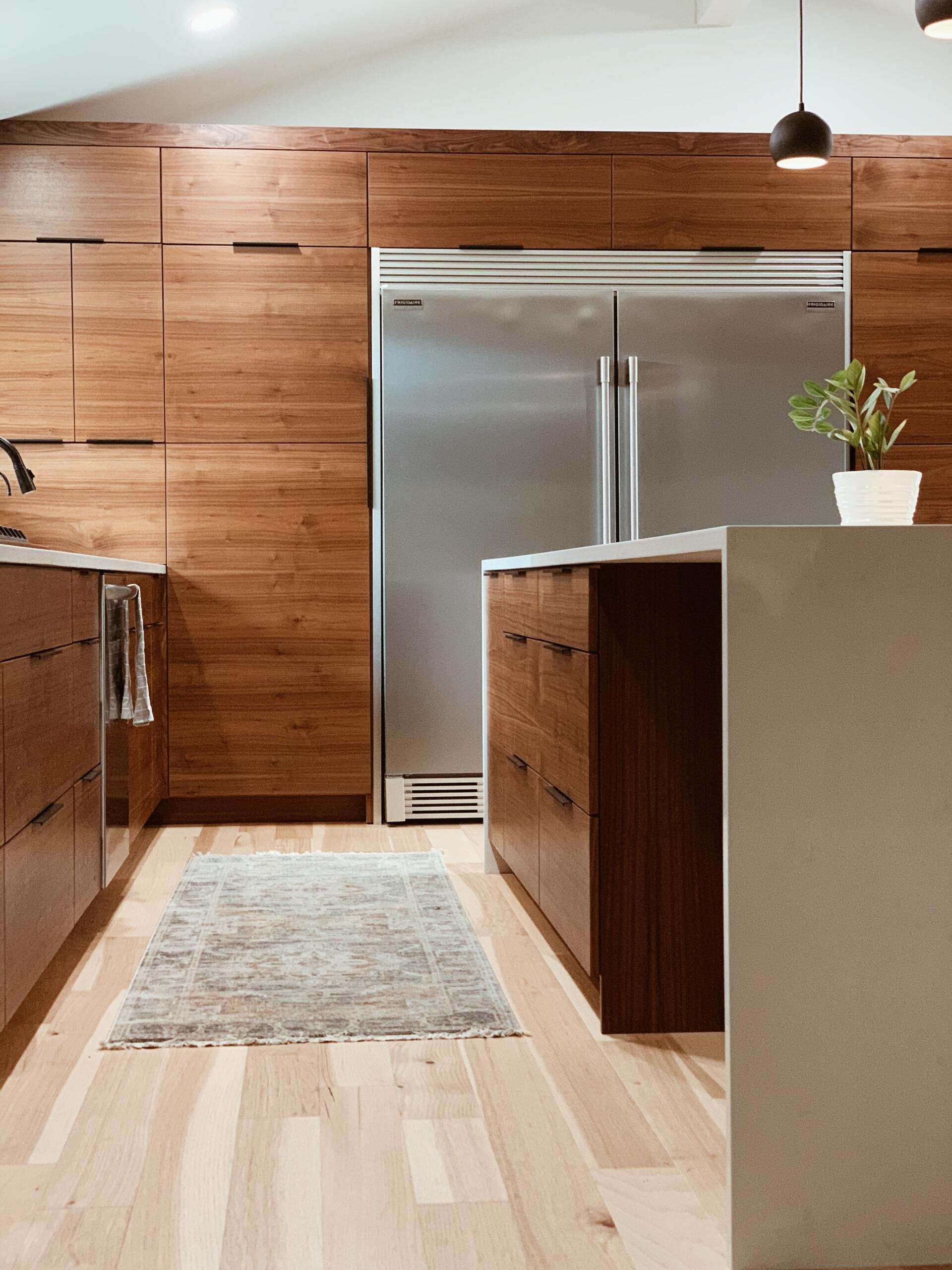 A modern kitchen with walnut cabinetry and maple flooring with a caption that says 