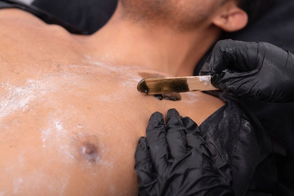 A man is getting a wax treatment on his chest.