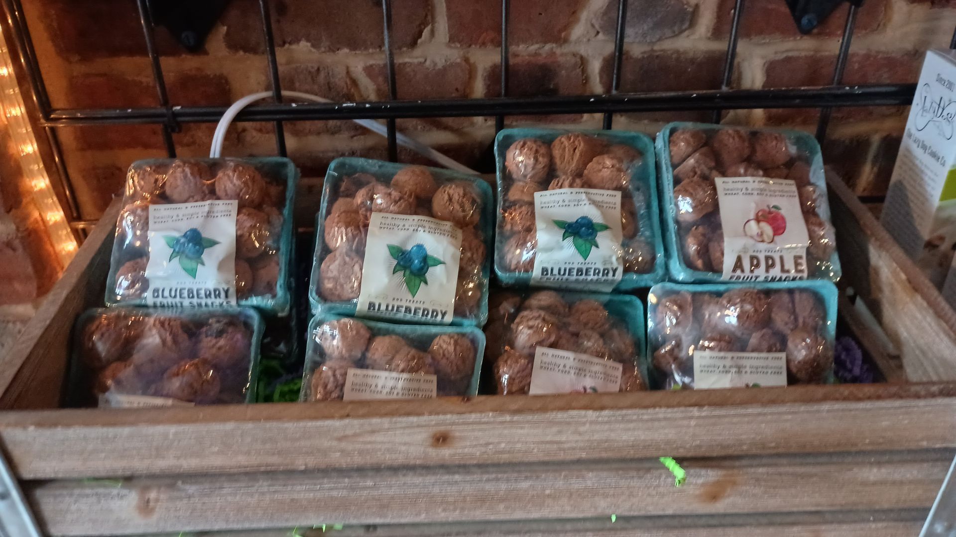 Blueberry and apple dog treats in farm-style crates on display at Smokey's Doggy Cafe.