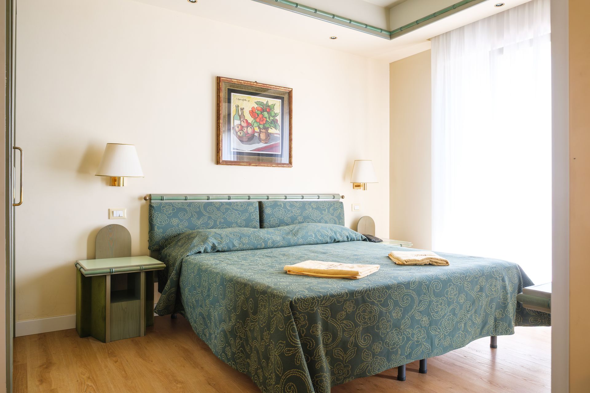A hotel room with a large bed and a painting on the wall.