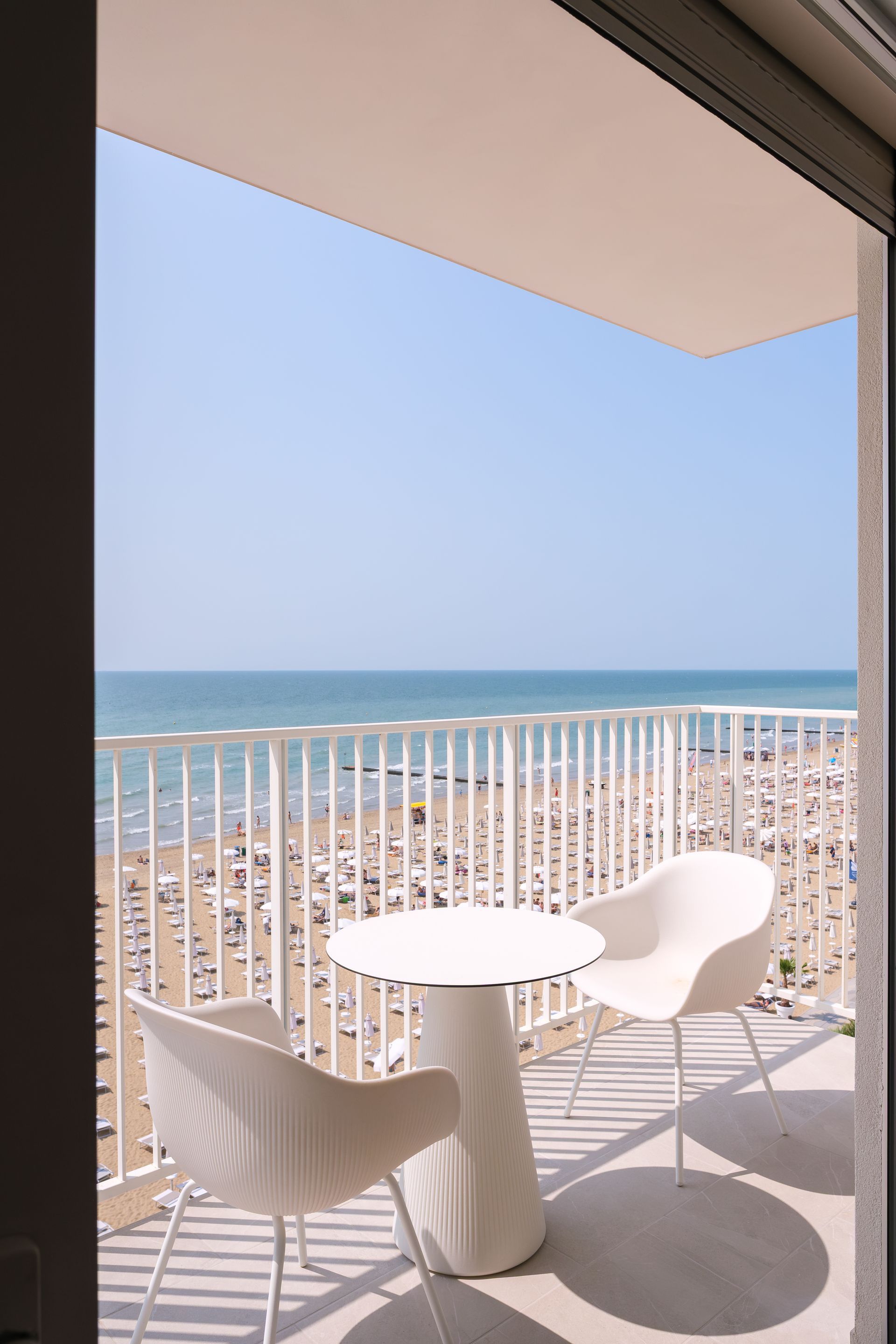 A balcony with a table and chairs overlooking the sea.