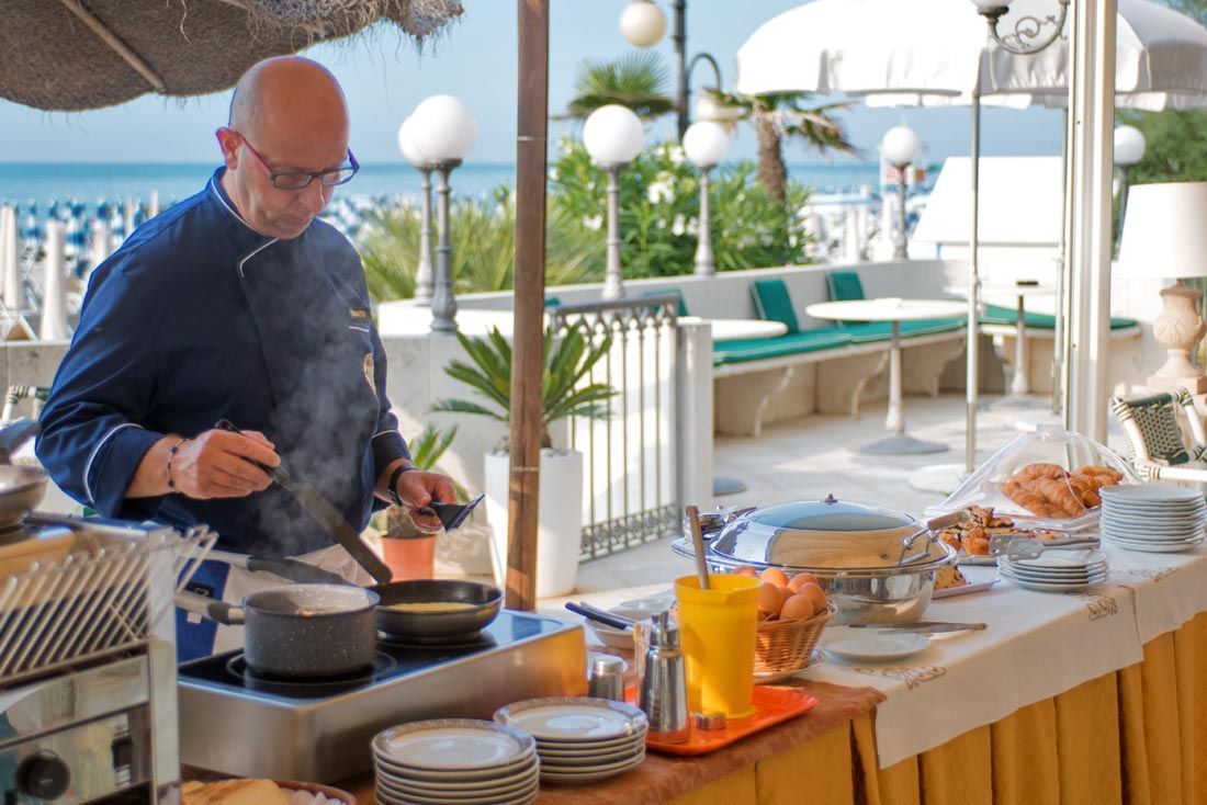 Un uomo sta cucinando del cibo su un fornello davanti a un tavolo da buffet.