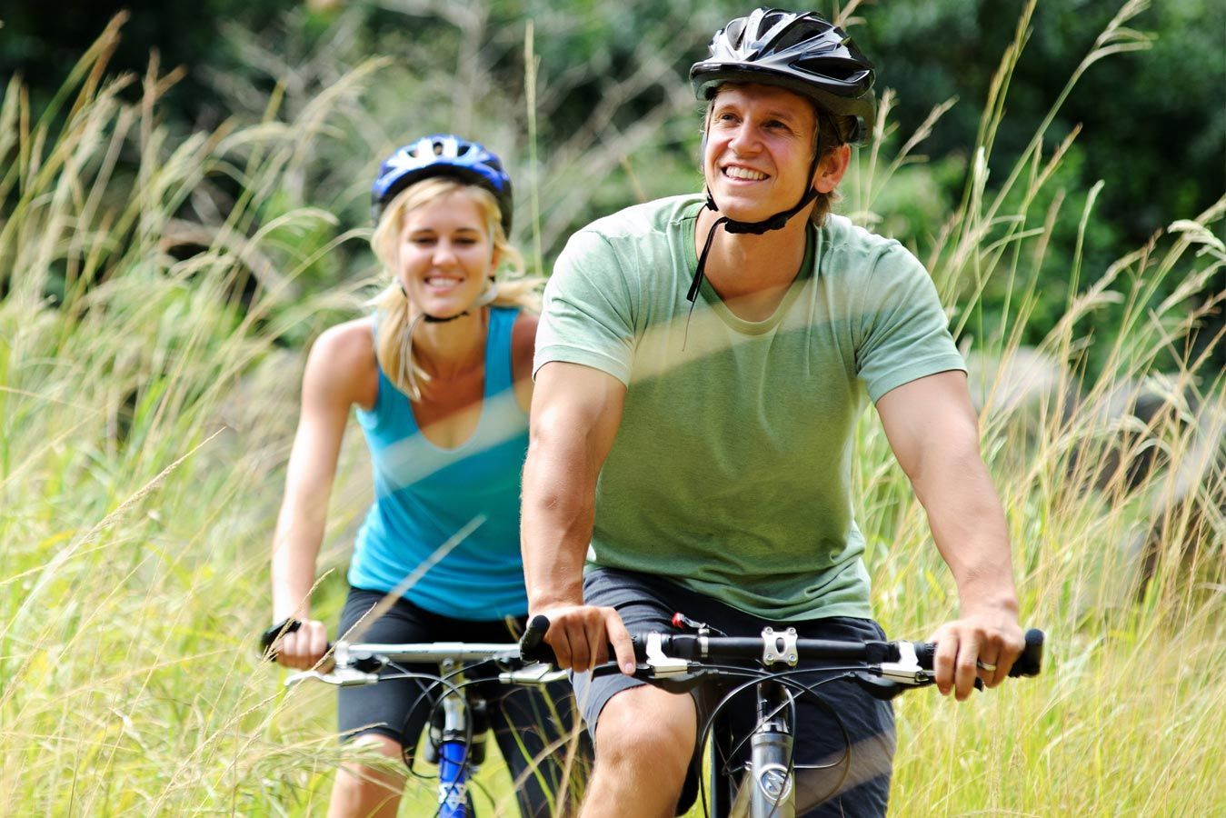 Un uomo e una donna stanno andando in bicicletta sull'erba.