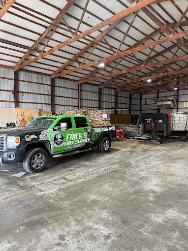 Green service pickup truck parked inside a large metal workshop with another truck in the background
