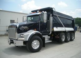 A black dump truck is parked in front of a white building