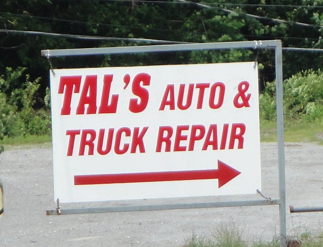 A sign for tal 's auto and truck repair with an arrow pointing to the right