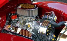 A close up of a red car engine with the hood open.