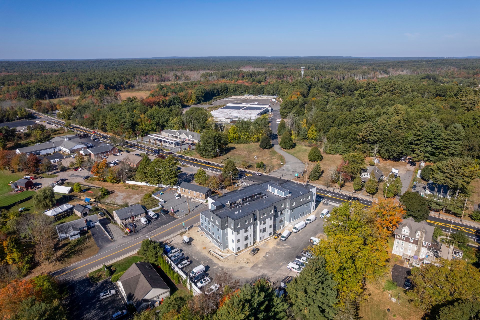 Aerial view of a multi-story building near a road and surrounded by trees and other buildings.