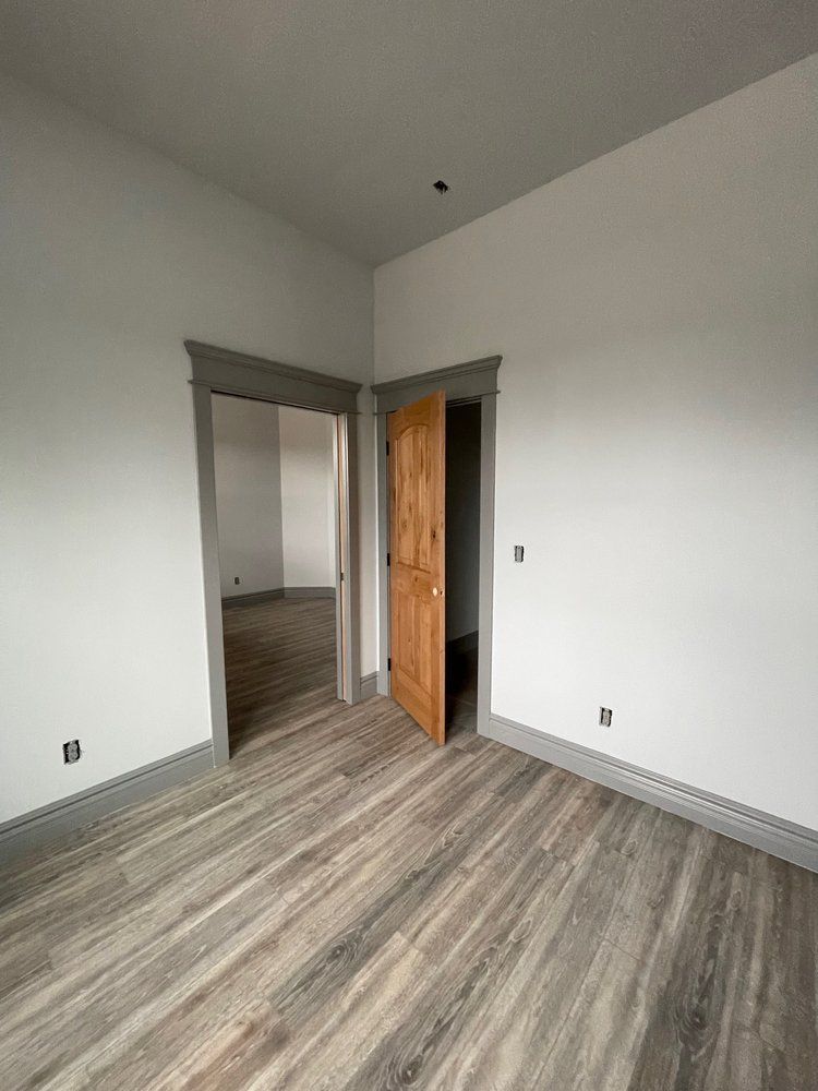An empty room with hardwood floors and white walls.