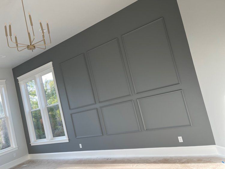 A living room with gray walls and white trim and a chandelier hanging from the ceiling.