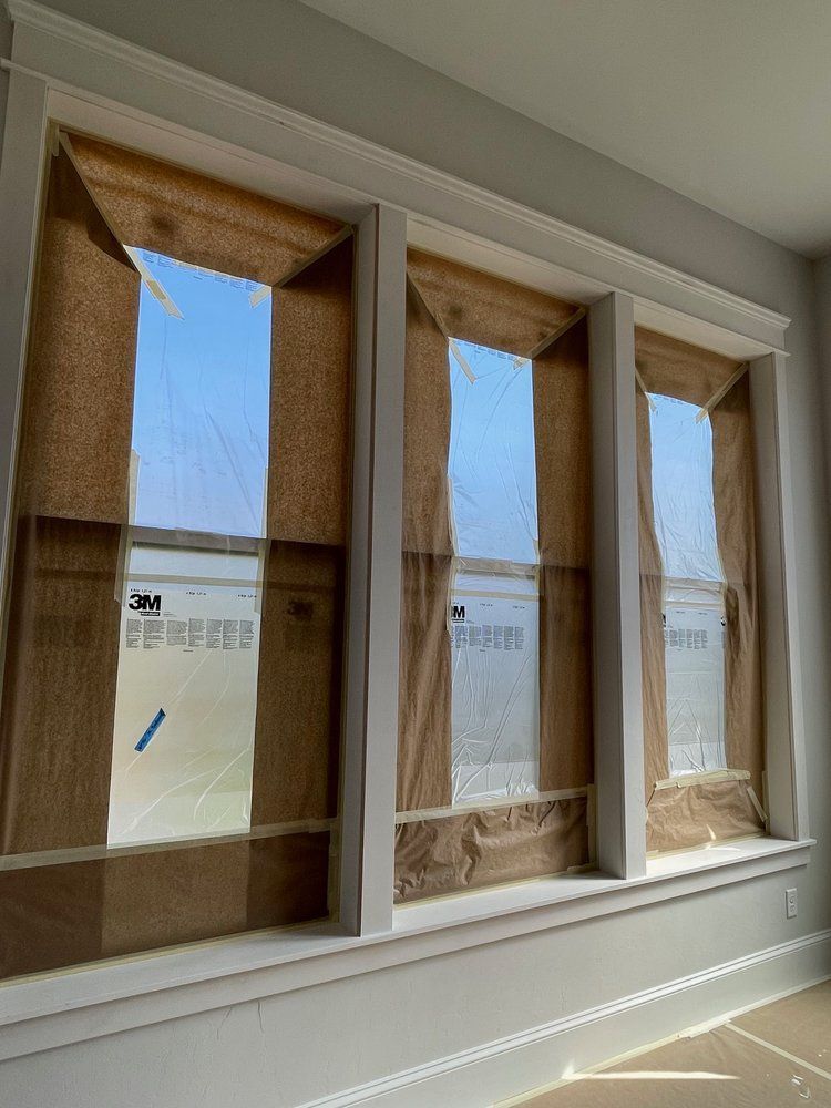 A room with three windows that are covered in burlap.