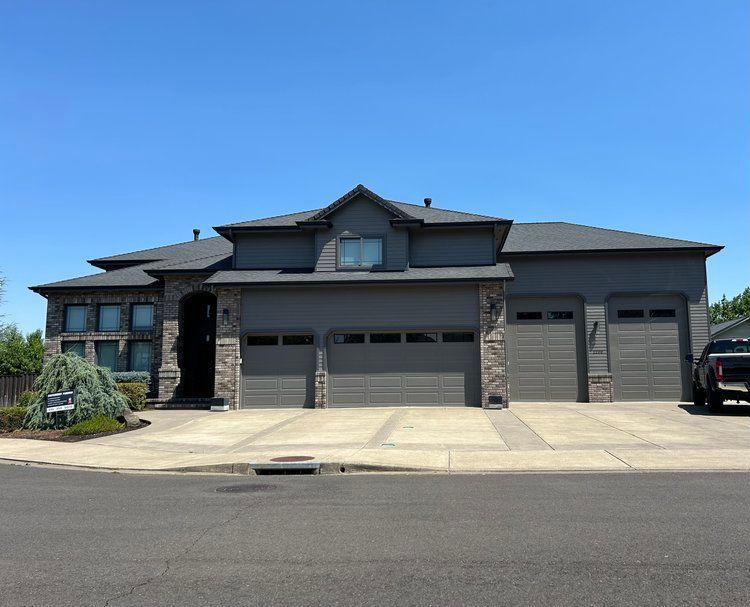 A large house with three garage doors and a truck parked in front of it
