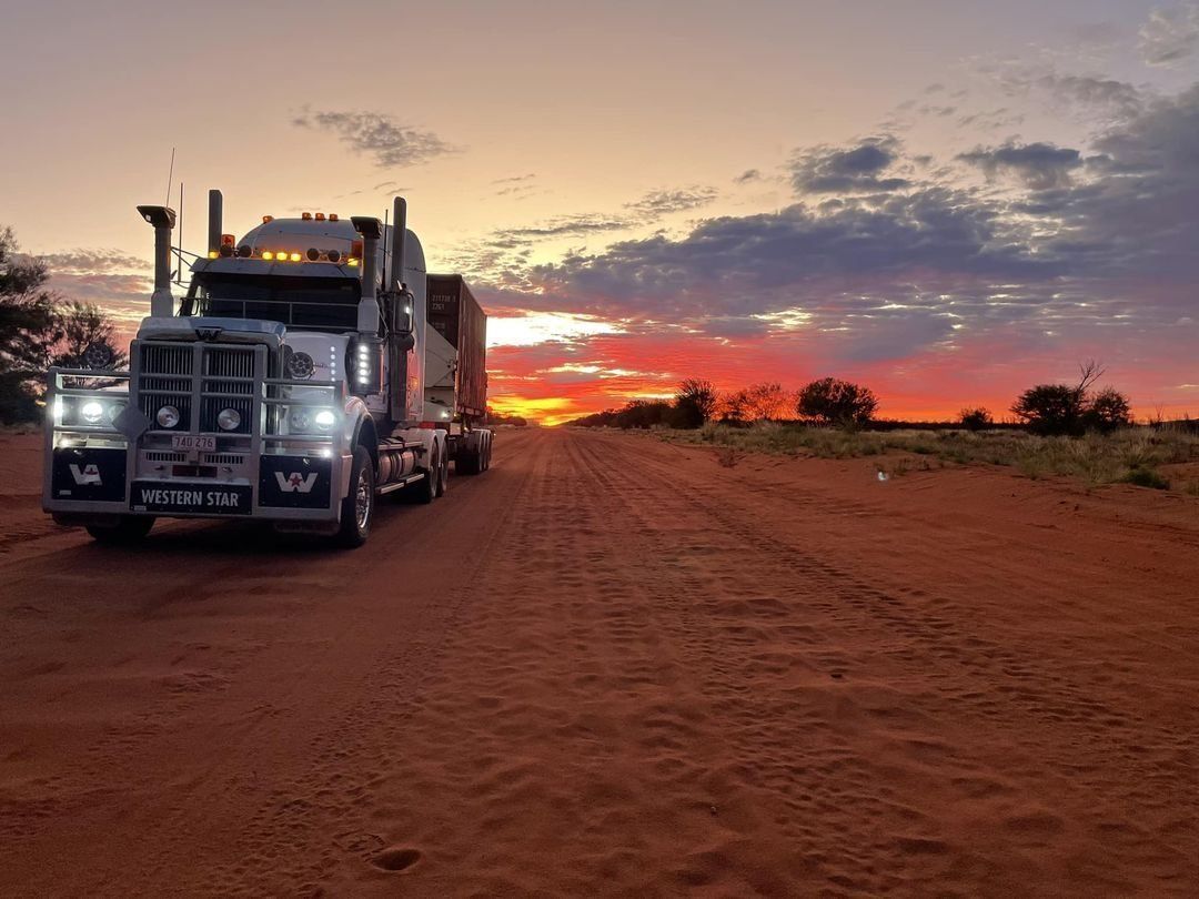 Semi-truck on a red dirt road at sunset — Central Australian Sidelifter Haulage in Ciccone, NT