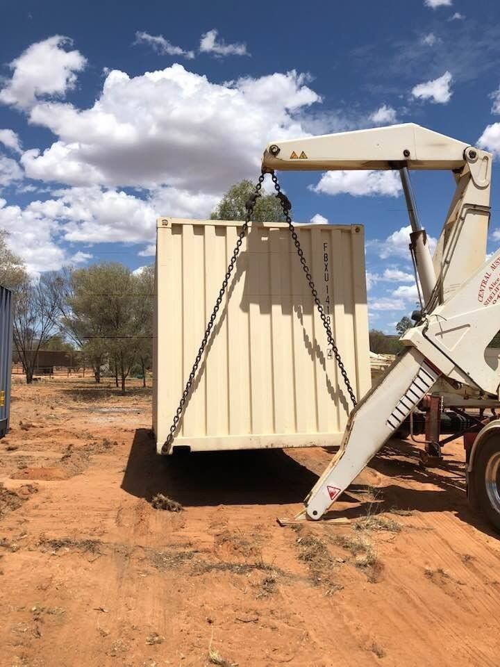 A Cream-Colored Shipping Container Suspended by A Crane — Central Australian Sidelifter Haulage in Ciccone, NT