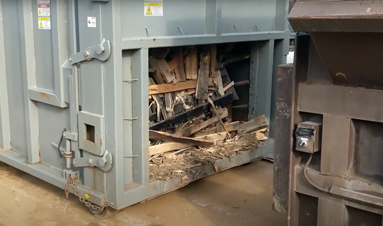 A dumpster with a lot of wood inside of it.