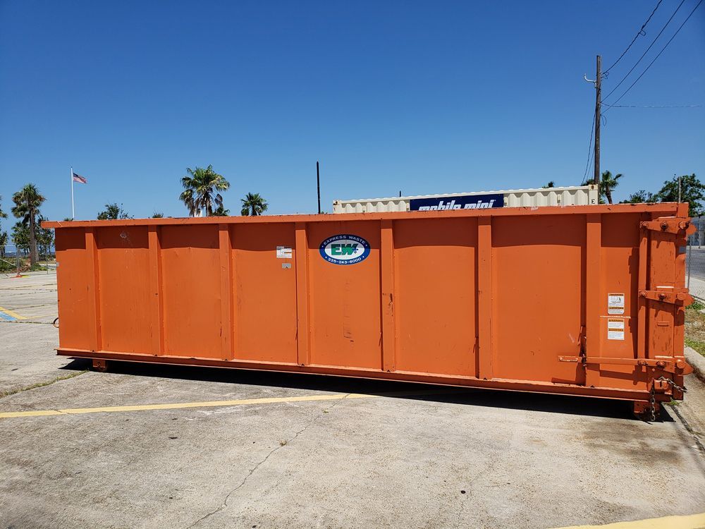 A large orange dumpster is parked in a parking lot