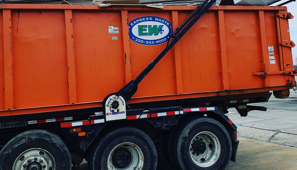 An orange dumpster truck with ew written on the side