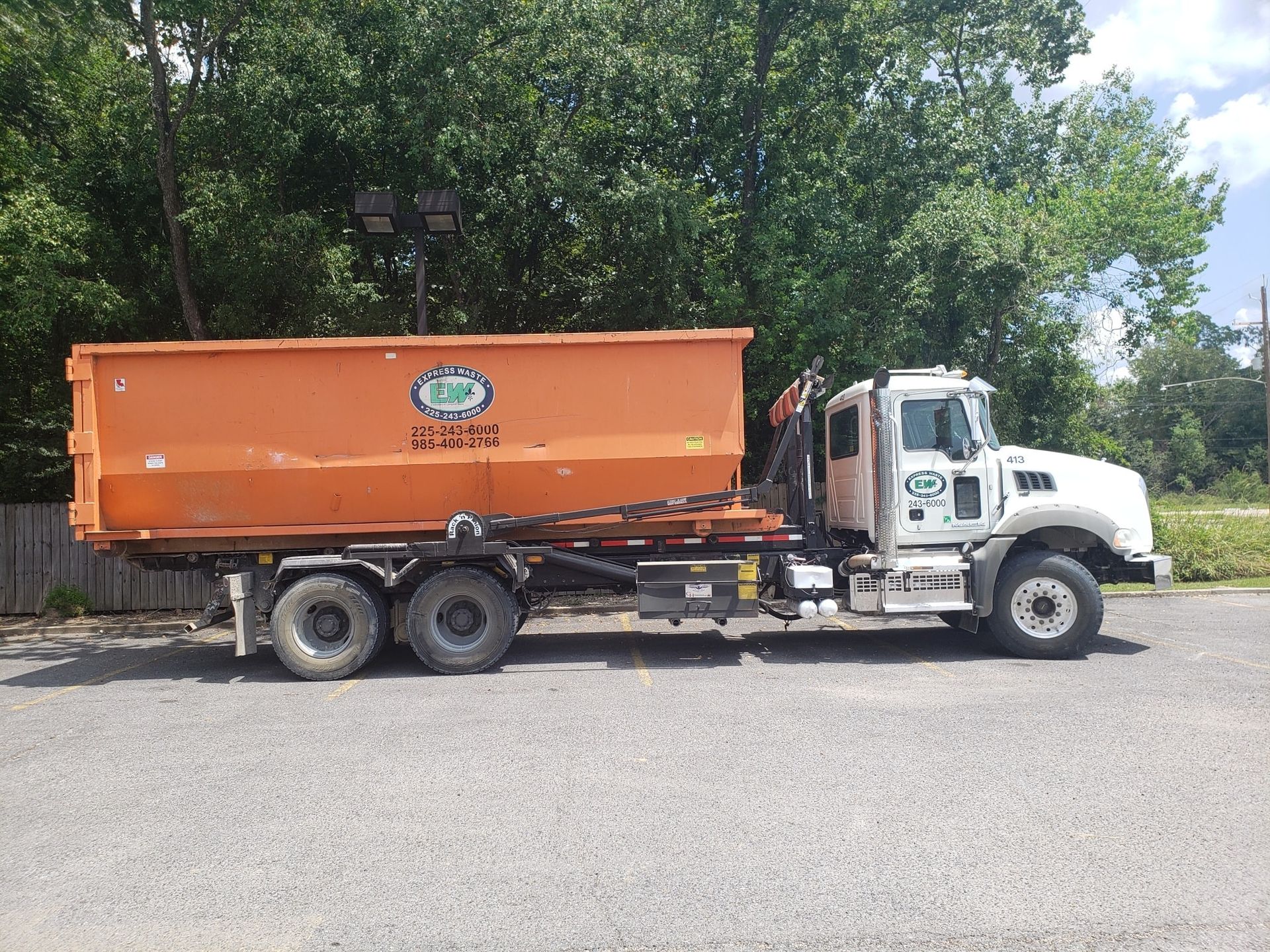 A dumpster truck is parked on the side of the road.