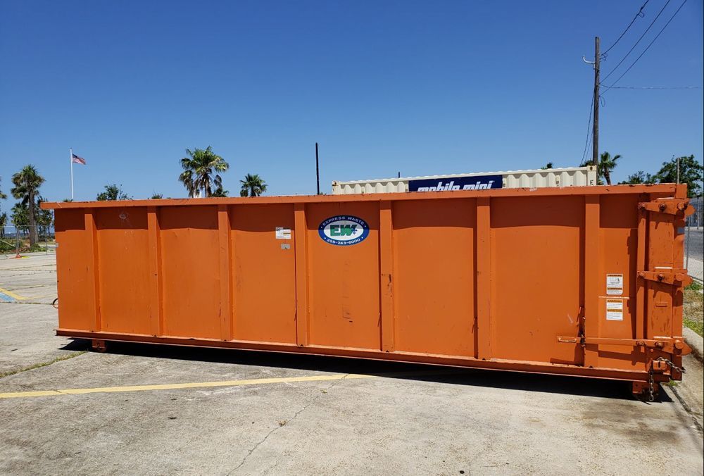 A large orange dumpster is parked in a parking lot