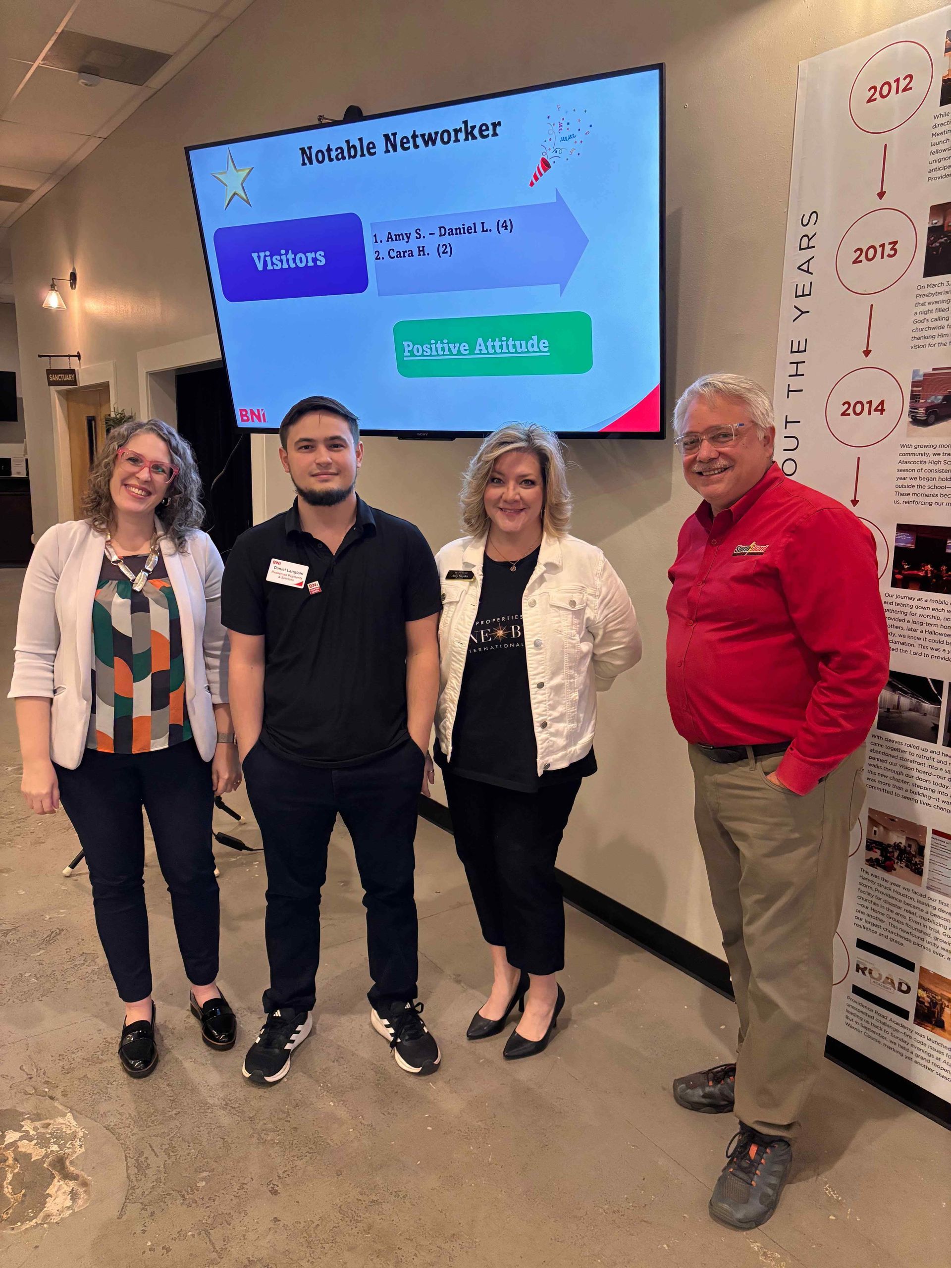 A group of people are standing in front of a large screen.