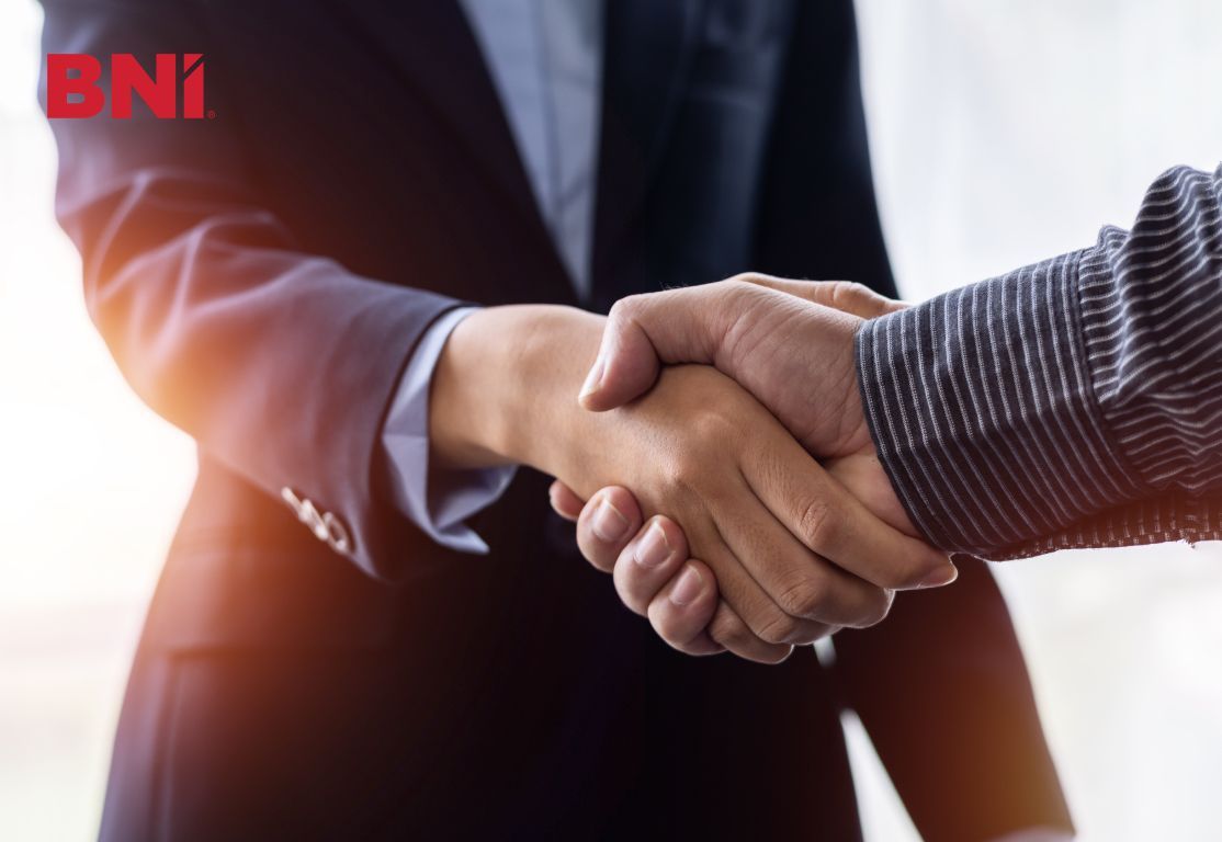 A man in a suit is shaking hands with another man in a striped shirt.
