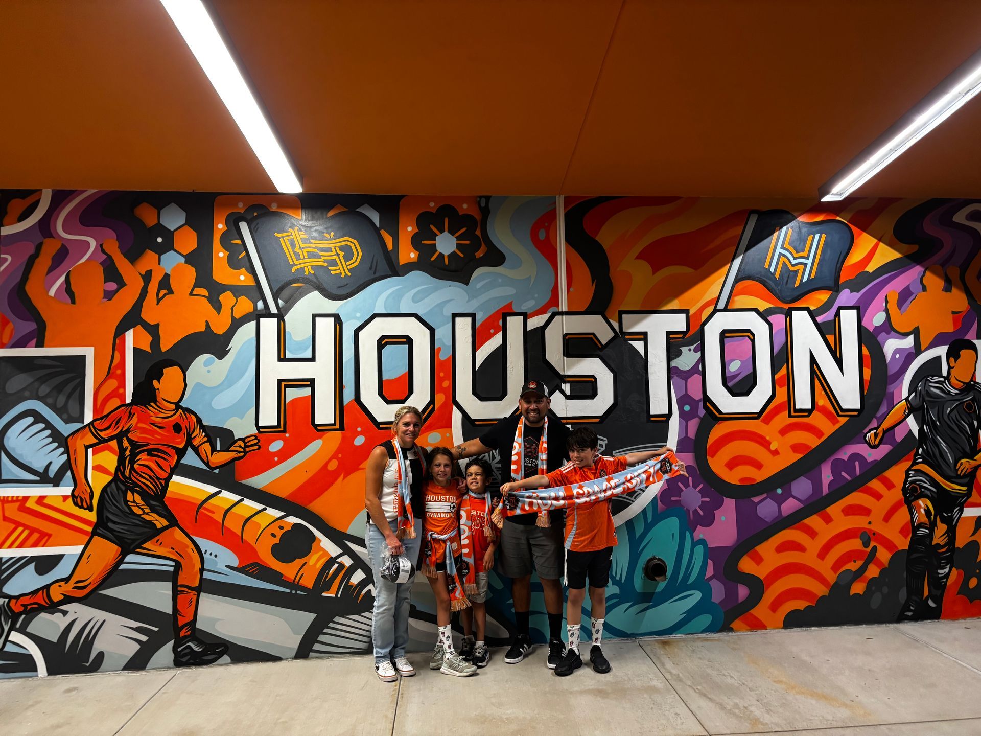 A group of people standing in front of a mural that says houston