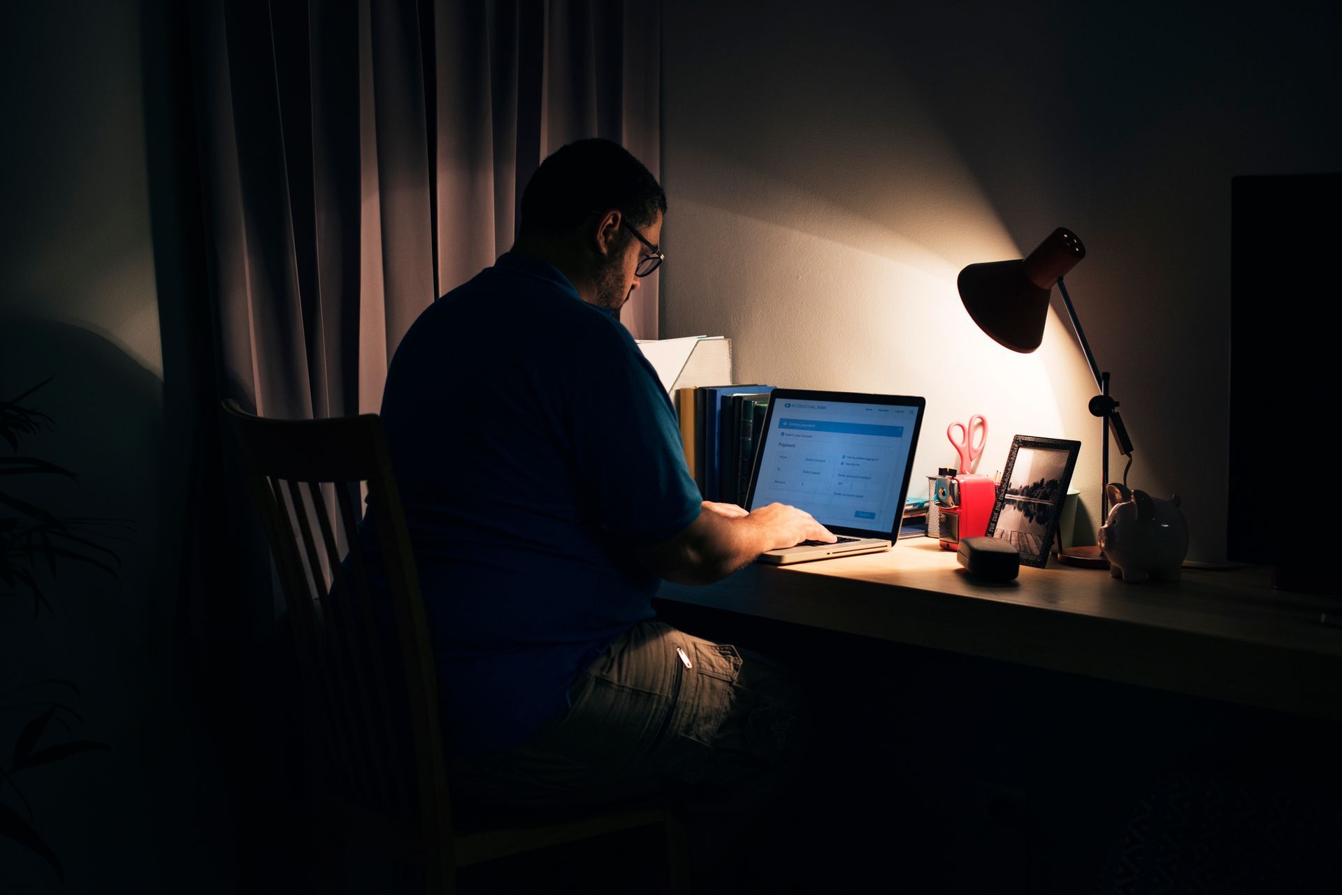 A person is typing on a laptop while sitting on a bean bag chair