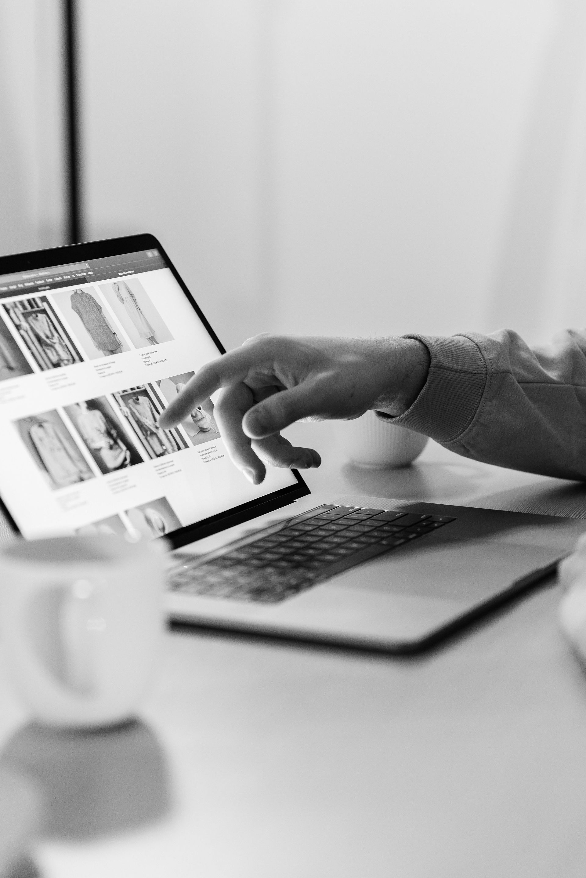 A black and white photo of a person using a laptop computer.