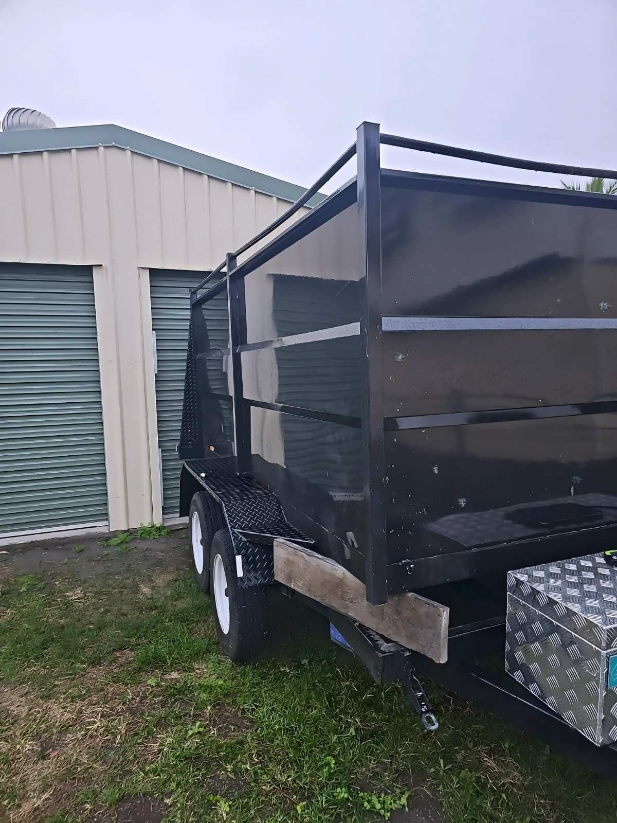 Black Trailer With High Sides, Parked Near a Storage Shed on Grass — NPX Solutions In Clairview, QLD