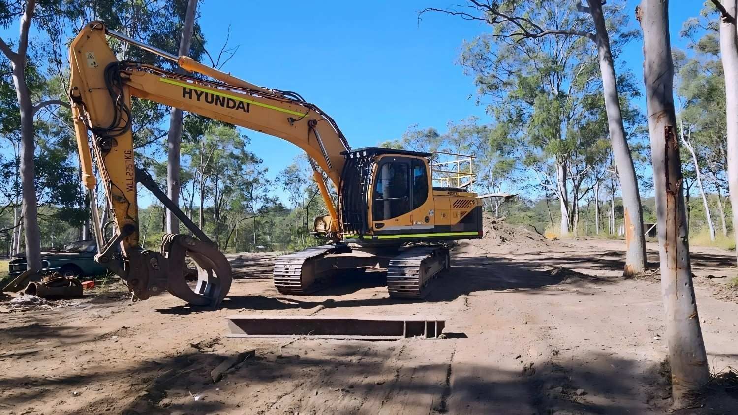 Orange Hitachi Excavator on a Flatbed Trailer Under a Blue Sky, in a Construction Site — NPX Solutions In Rockhampton City, QLD