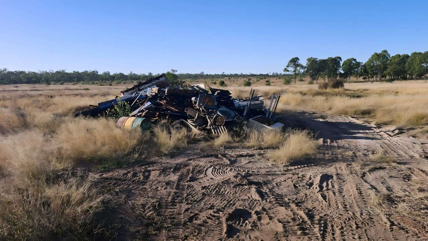 Pile of Mangled Metal Wreckage in a Field of Dry Grass Under a Blue Sky — NPX Solutions In Clairview, QLD