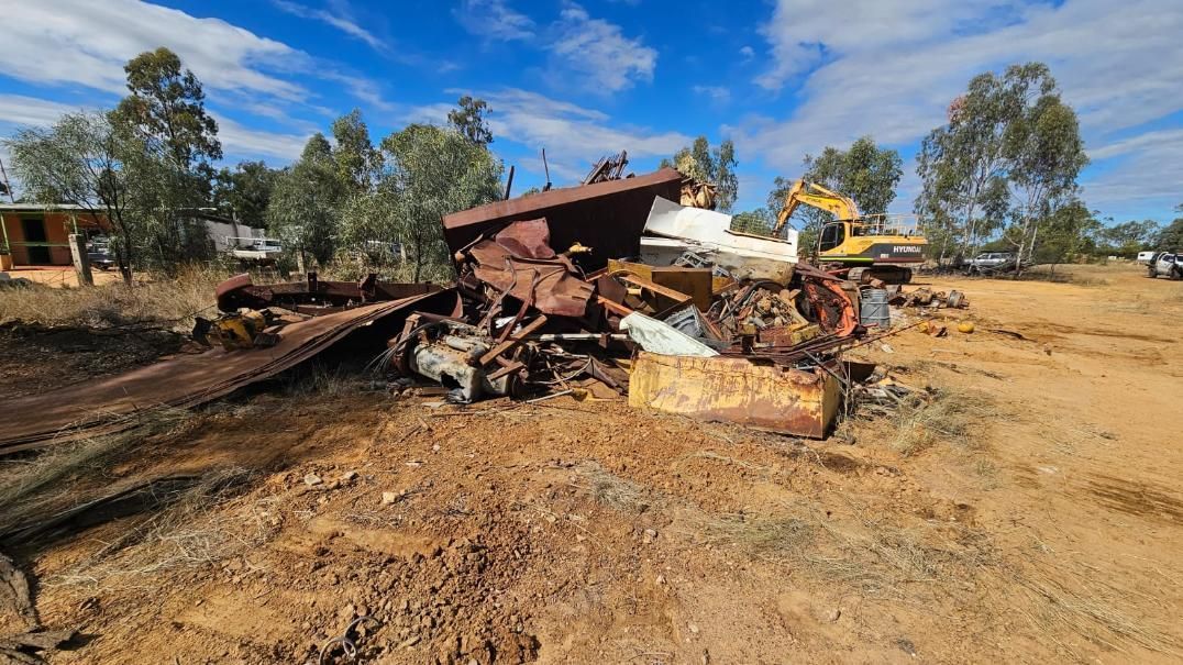 Demolished Rusty Structure With Excavator in a Dry, Rural Landscape Under a Blue Sky — NPX Solutions In Rockhampton City, QLD