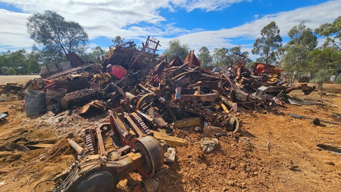 Pile of Rusty Metal Scraps and Vehicle Parts on Dry, Reddish Earth. Trees — NPX Solutions In Rockhampton City, QLD