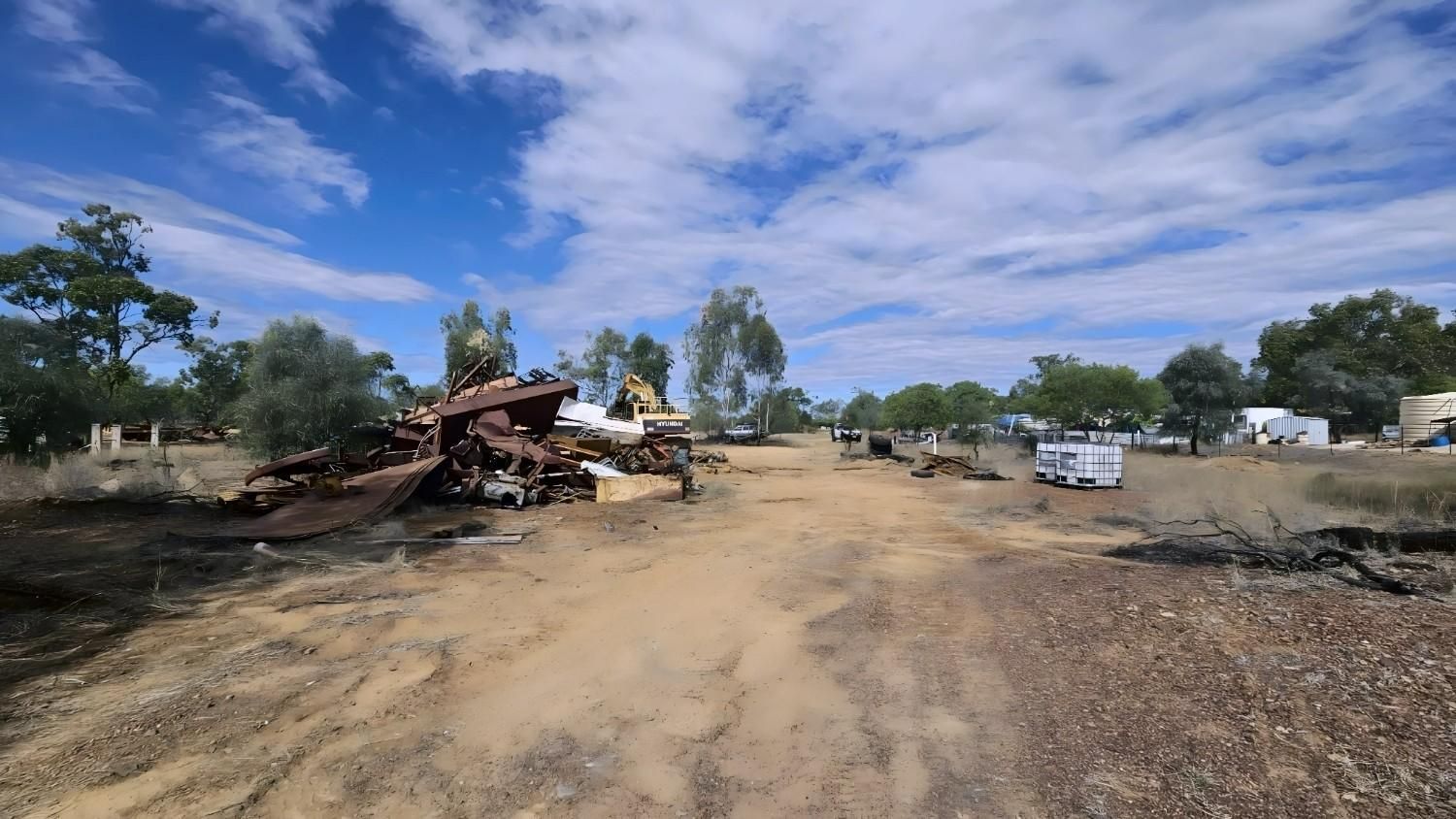 Dirt Road Through a Sunny, Sparse Landscape With Trees, Debris, and a White Vehicle — NPX Solutions In Middlemount, QLD