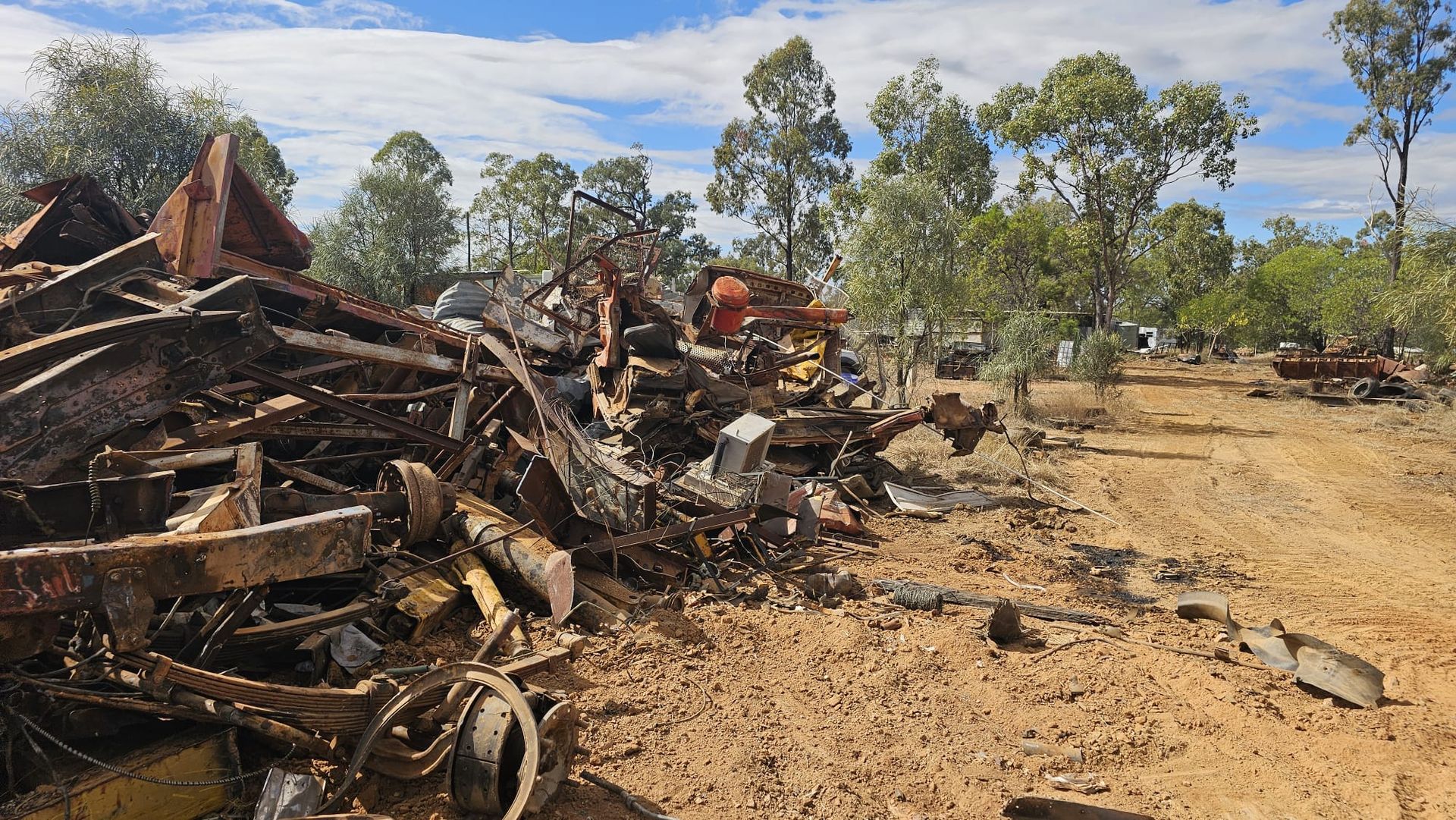 Pile of Rusty Metal, Possibly Scrap, Next to a Dirt Road in a Dry, Wooded Area — NPX Solutions In Rockhampton City, QLD