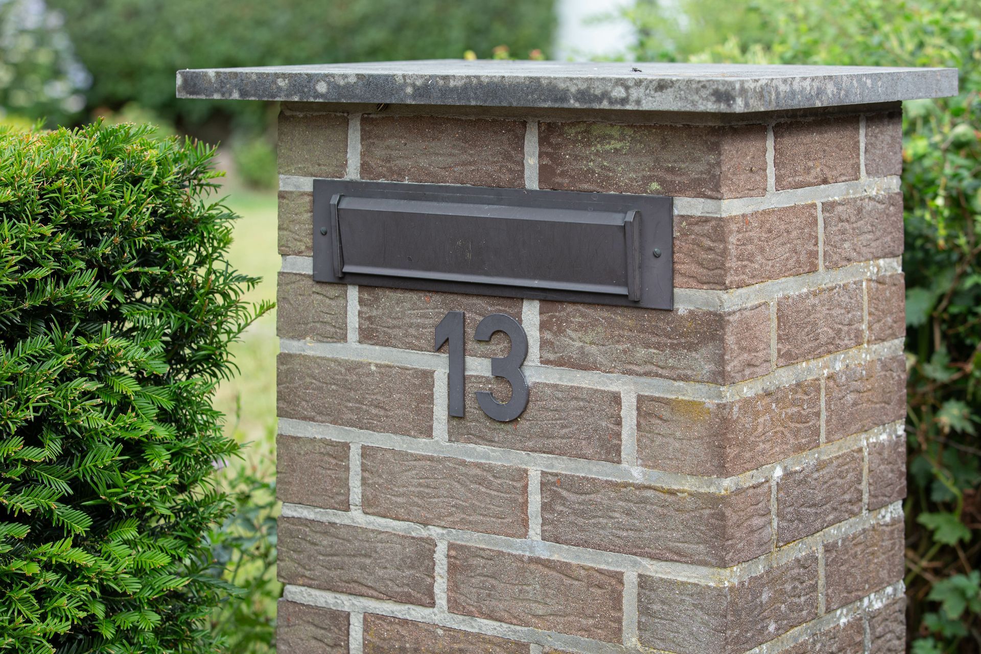 Brown brick mailbox in a suburban neighborhood.