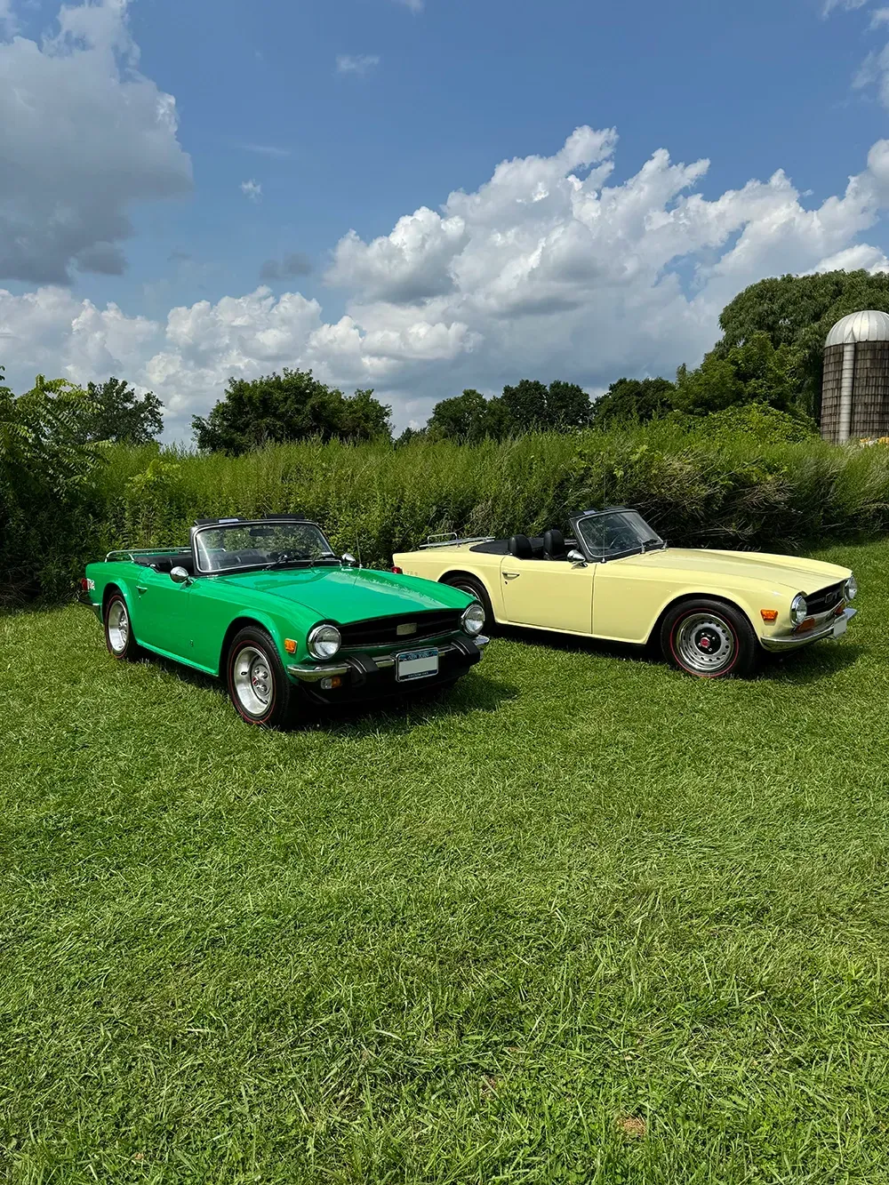 One green classic car and one yellow classic car parked in grass outside | Gerry's Service