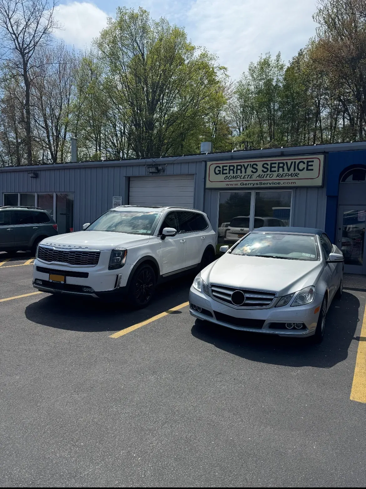 White KIA SUV and White Mercedes-Benz parked in front of our shop | Gerry's Service
