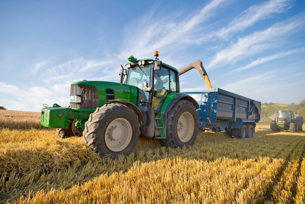 Tractors Attached With Trailers Harvesting Wheat Across A Rural Field — O'Brien's Machinery In Dubbo