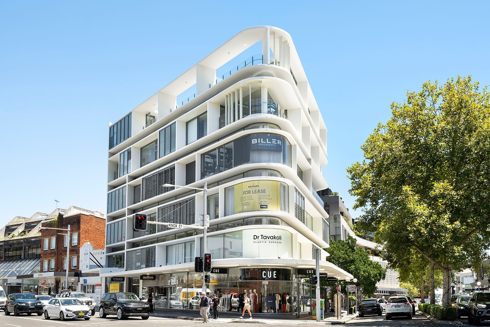 A large building with a lot of windows is on the corner of a city street.