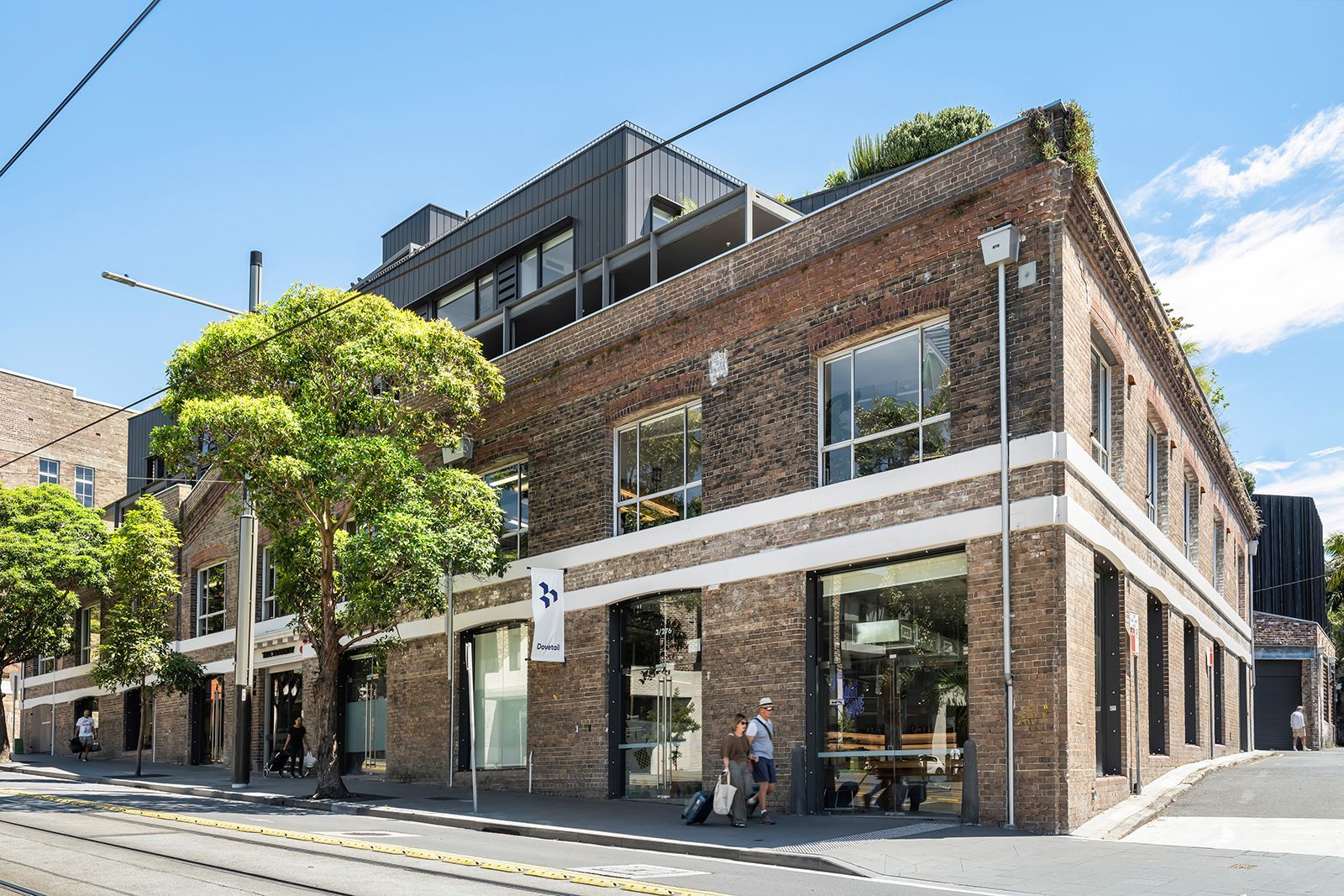 A large brick building with a lot of windows is on the corner of a street.