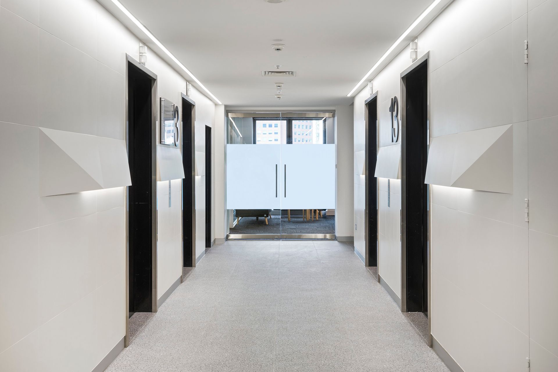 A long hallway with a glass door in the middle of it