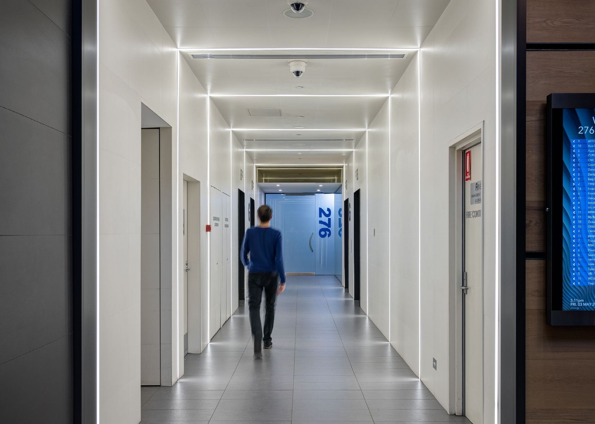 A man is walking down a long hallway in a building.