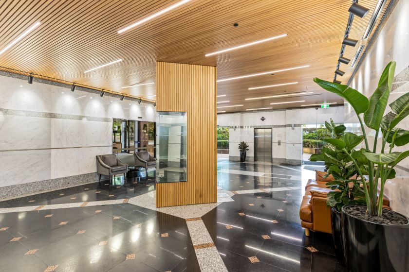 A large lobby with a couch , chairs , and potted plants.