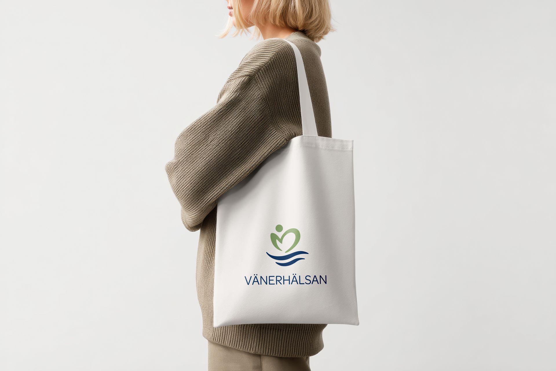 Tygp&aring;se med V&auml;nerh&auml;lsans logotyp p&aring;. En kvinna st&aring;r i profil med p&aring;sen &ouml;ver axeln.