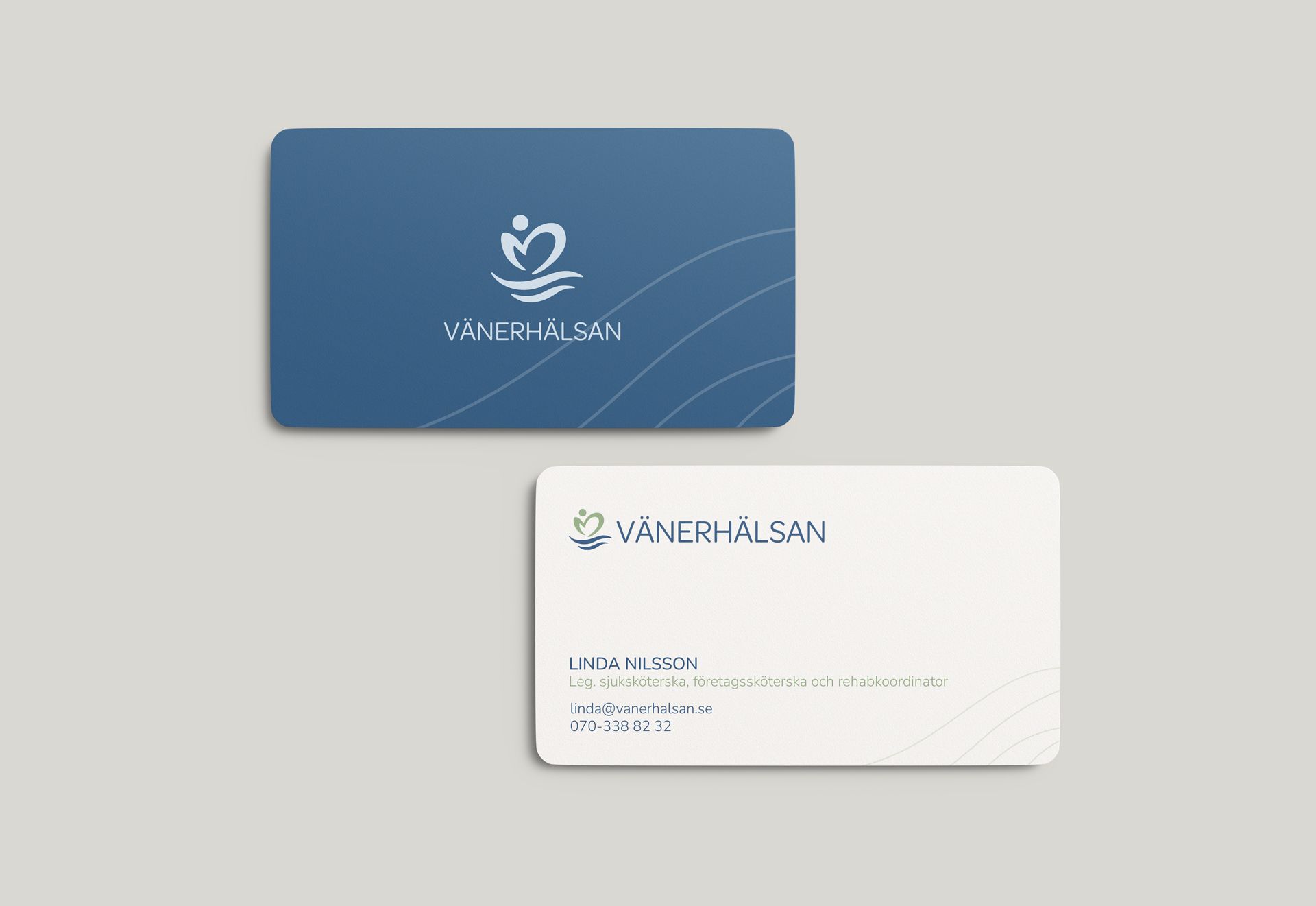 Exempelbild p&aring; V&auml;nerh&auml;lsans visitkort. Visar b&aring;de fram och baksida. Framsidan i bl&aring; botten med ljusbeige logotyp och baksidan i ljusbeige botten med logotyp och kontaktinformation.